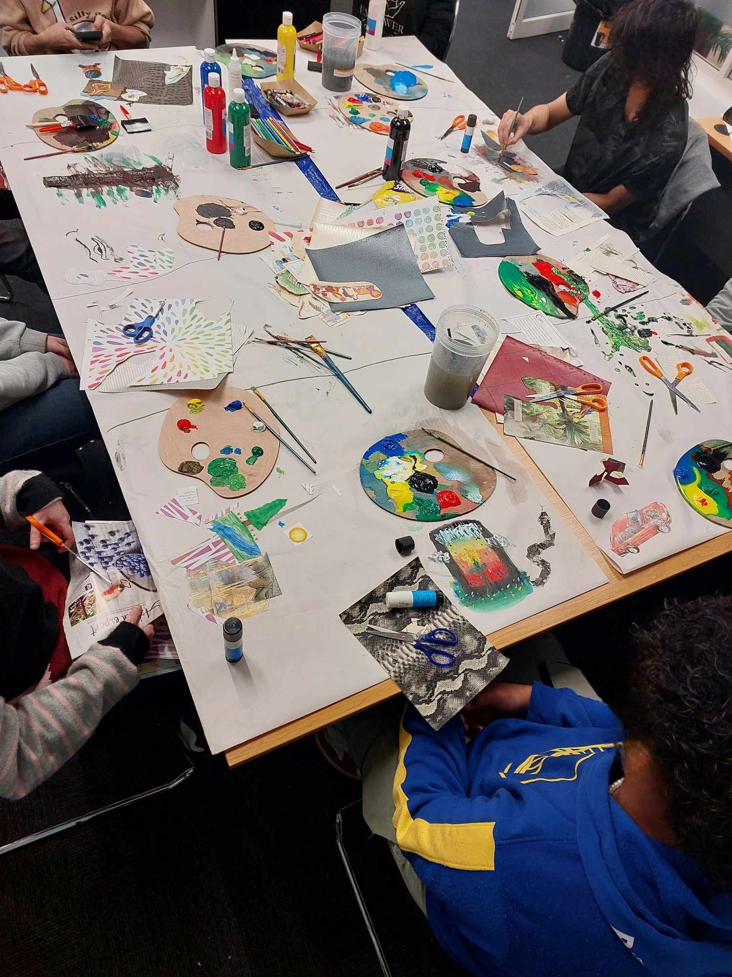 A group doing art together used mixed media on large papers.